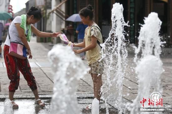7月25日，市民在南京街头的喷泉处戏水觅清凉。 <a target=
