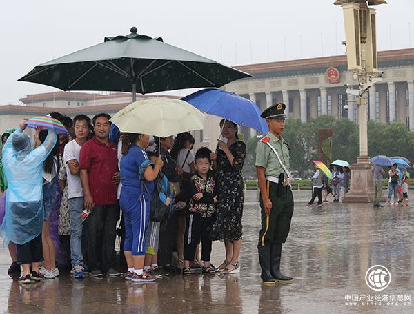 天安门广场一执勤武警将岗伞让给群众避雨，自己冒雨站岗