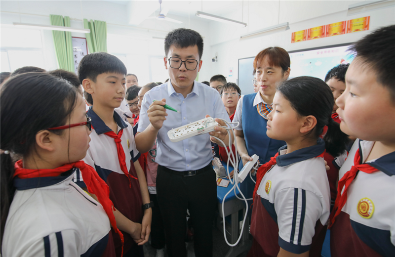 5月31日,兰山区银雀山街道银雀山小学,供电系统工作人员正在为小学生